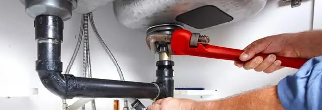 Garbage disposal repair technician tightening the sink drain and disposal connection in Myrtle Beach, SC