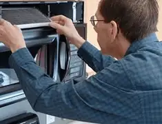 Appliance repair technician replacing a microwave vent filter in Myrtle Beach, SC