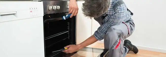 Oven repair technician inspecting and servicing an electric oven in Myrtle Beach, SC