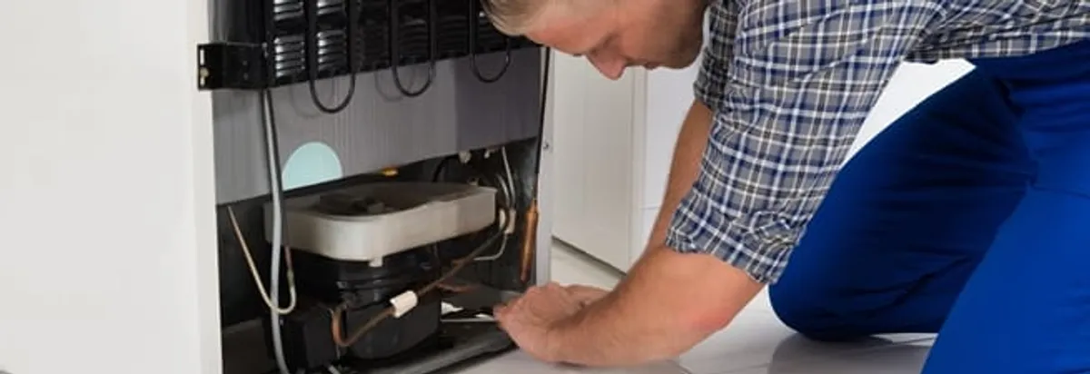 Refrigerator repair technician servicing the compressor and condenser area in Myrtle Beach, SC