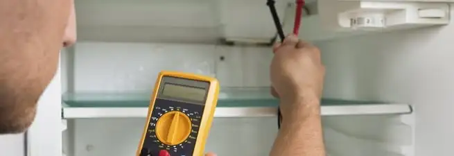 Refrigerator repair technician testing electrical components with a multimeter in Myrtle Beach, SC