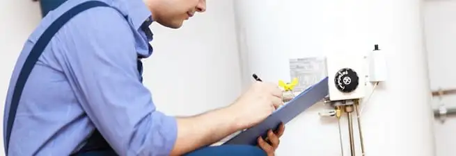 Water heater repair technician inspecting the unit and recording service notes in Myrtle Beach, SC